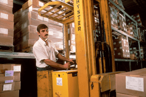  man driving forklift to move pallets of boxes